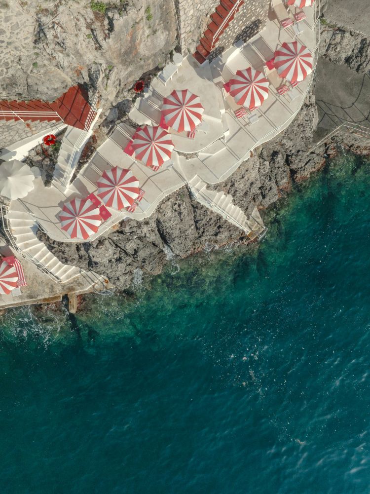 Palazzo Avino si trova circa 350 metri sopra il mare, ma dispone di un accesso privato all’acqua a Marmorata, raggiungibile con una navetta. Il contrasto è parte dell’esperienza: si dorme sulla montagna, in uno dei punti più panoramici della Costiera, e si scende al mare in un club ricavato su terrazze e piattaforme affacciate direttamente sull’acqua