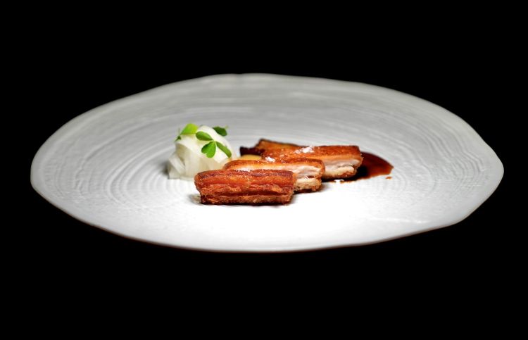 Pancia di maialino croccante: pancia di maialino croccante glassata con salsa char siu, servita con tagliatella di daikon marinato all’aceto di riso, melanzana cinese agropiccante e una salsa cremosa a base di senape antica, miele, soia e fondo bruno