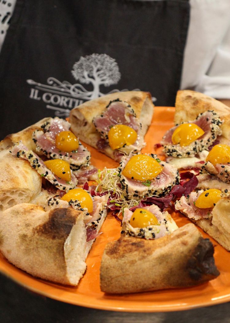 La pizza Pavonia con fiordilatte, cipolla caramellata, tonno rosso in tataki di semi di sesamo e papavero, pomodorini gialli confit, aneto, olio evo al bergamotto