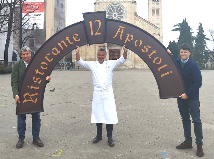 Antonio and Filippo Gioco, father and son, hold up the 12 Apostoli sign, a restaurant made famous in Verona by Giorgio Gioco. In the middle a smiling Giancarlo Perbellini, the restaurant's new patron
