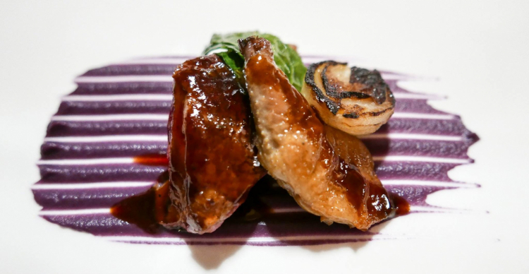 Piccione arrosto servito al sangue con cipolle alla brace, variazione di cavolo e salsa agrodolce piccante
