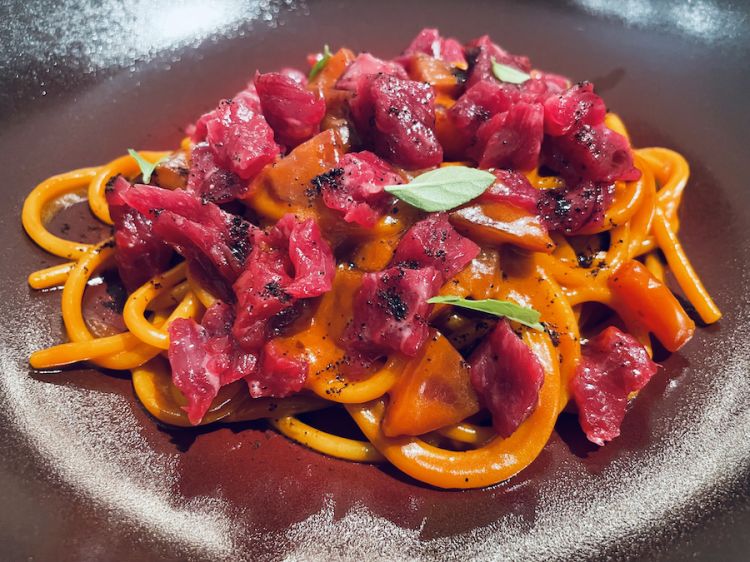 Spaghetti Mancini di grano duro cotti in succo di peperoni arrostiti, prugne fermentate, battuta cruda di vacca vecchia e olio al caffè, un primo dell'Enoteca Pinchiorri di Firenze, menù dell'estate 2022
