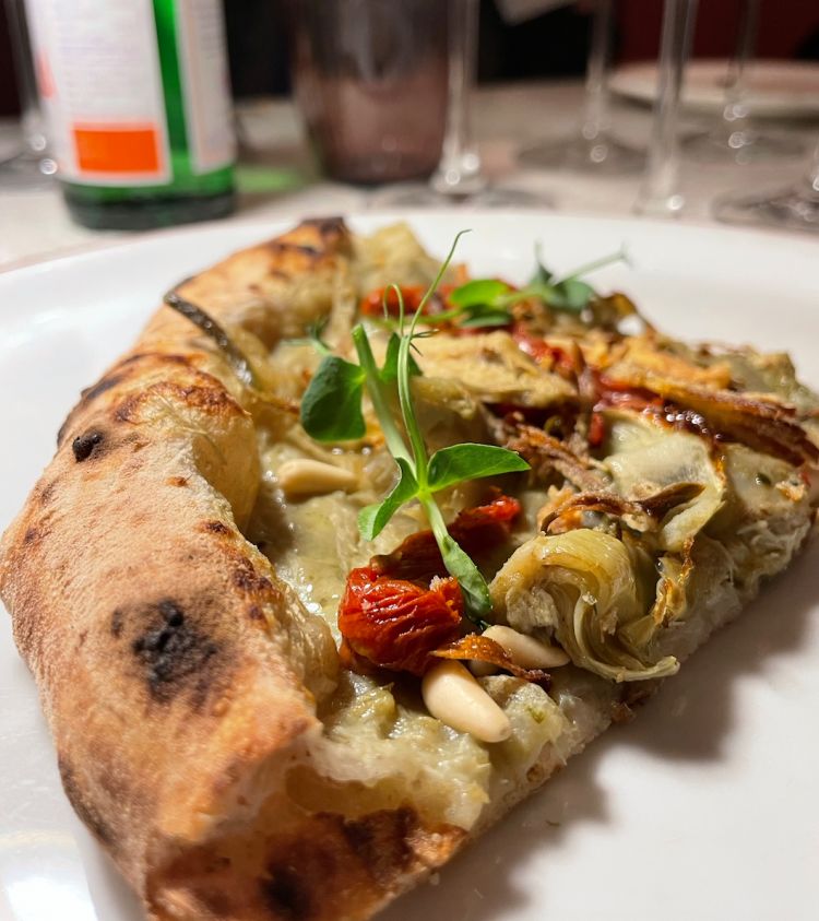 Pizza con crema di carciofi, carciofi alla romana, carciofi fritti, pomodori secchi, pinoli e germogli di piselli