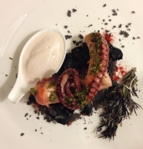 Grilled squid on a bed of potatoes with squid ink and steaming rosemary 