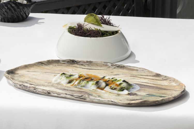Seppia con ricci di mare e mela verde. Seppia cotta a bassa temperatura con ricci di mare, mela verde e polvere di nero di seppia; in appendice, un raviolino d’alga ripieno con seppia marinata in olio, sale, pepe ed essenza di acqua di mare