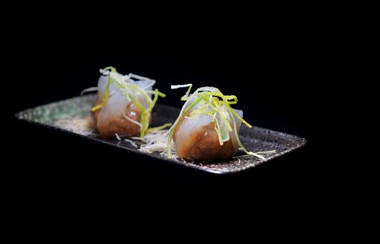 Ravioli all’anatra piccante: ravioli ripieni di anatra piccante e guarniti con ciuffi di porro croccante
