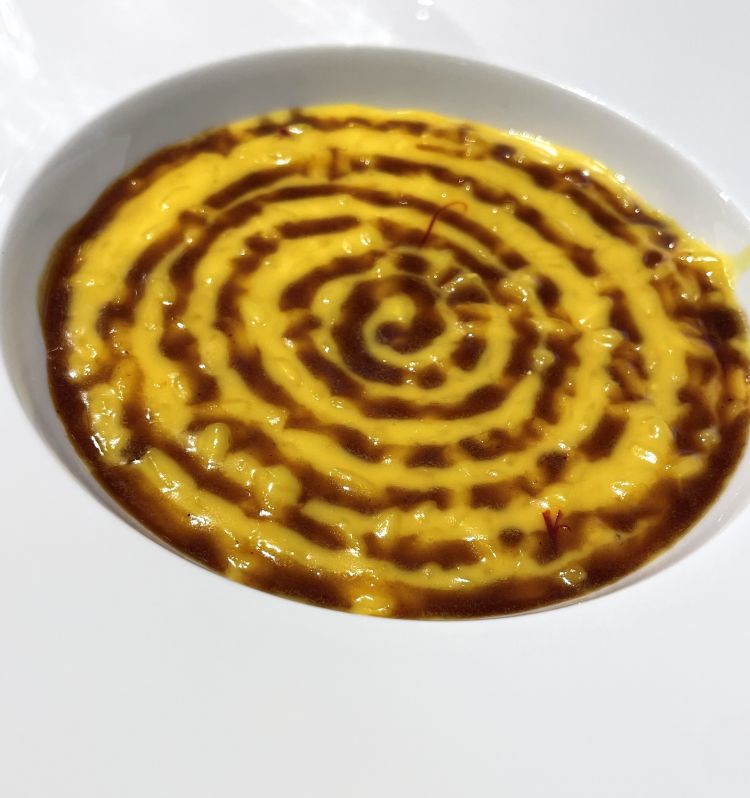 “Succo di vitello”, profumo di gremolada milanese, riso e zafferano. Un risotto alla milanese, classico, equilibrato nella sapidità e nell’impronta dello zafferano che non assuefà il palato. In questo caso parliamo di jus di vitello, che disegna una spirale in superficie. Nulla a che vedere con una scelta puramente estetica, perché pensata per accompagnare ogni boccone dell’ospite, così in grado di assaporare tutti gli ingredienti, anche conversando e mangiando distrattamente