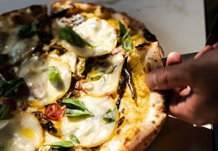 La pizza Sant'Eligio con funghi champignon, castagne e cipolla, brie, pancetta tesa, julienne di radicchio marinato all'aceto di lampone, funghi di stagione cotti a legna, olio Evo