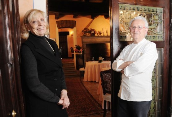 Ezio e Renata Santin sulla porta d'ingresso della loro Antica Osteria del Ponte alla Cassinetta di Lugnagnano. Un anedotto raccontato durante Identità Expo: il salottino di benvenuto venne allestito quando la Michelin avvisò i coniugi Santin di non avere ottenuto la terza stella perché, alla visita decisiva, i vertici della guida rossa, arrivati in anticipo per pranzo, trovarono il personale che mangiava quasi sull'uscio. "Non è da locale tre stelle", la sentenza che spinse Ezio e Renata a cambiare tutto lo spazio. Accadde nel 1988, la terza stella arrivò l'anno seguente con l'edizione 1990, presentata nel novembre 1989. La foto è presa da ViviMilano