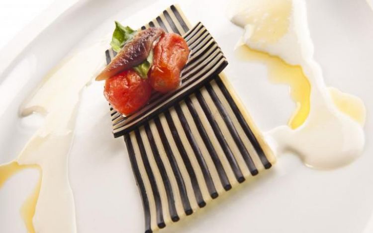 2011: Spaghetti Pizza Margherita di Davide Scabin

Ormai è storia nota ai più. Il grande produttore di pasta Riccardo Felicetti nel 2008 va a cena da Davide Scabin al Combal.Zero: «Gli chiesi - racconta - perché non tenesse alcun piatto di pasta secca in menu. Lui rispose: perché è banale. Tornai dopo sei mesi con un pacco della mia pasta e gli dissi: "La sbanalizzi, la prego"». Scabin prese sul serio l’invito di Felicetti: «Impiegai due mesi per capire cosa volessi dalla pasta. Avevo chiuso da un pezzo il mio ciclo legato alla progettazione e packaging delle forme, ma la pasta mi riconduceva violenta a quella dimensione. Conoscete un oggetto più di design di uno spaghetto o di un conchiglione?». Da questa riflessione nascono gli Spaghetti Pizza Margherita, spaghetti alternati a spaghetti al nero di seppia reidratati e messi sottovuoto anche 4 giorni in frigorifero, poi scaldati al microonde e conditi a piacere (“Pizza Margherita” perché la scelta dello chef era caduta su salsa di tomato blend, crema di burrata e foglie di basilico). La ricetta

