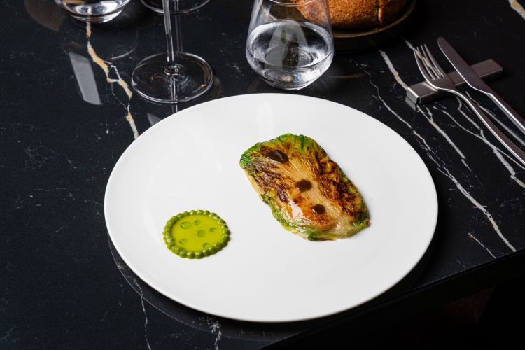 Scarola &ldquo;&rsquo;mbuttunata&rdquo;: scarola ripiena di pane al miso di fagioli, patate, olive, capperi, noci ed estratto di scarola alla scapece. Si tratta di una scarola rosolata ripiena di pane al miso di fagioli, patate, olive, noci e capperi. A parte viene servito un estratto di scarola alla scapece che, con la sua acidit&agrave;, bilancia la scarola ripiena.&nbsp;In abbinamento, un calice di Domaine Carrion Chablis 2022 che accompagna&nbsp;anche il piatto successivo
