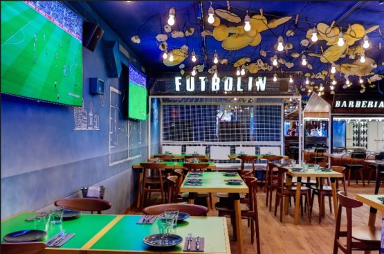 Bar del Pueblo, with maxi screens and a barber shop in the background
