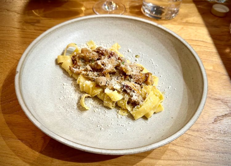 Tagliatella al ragù di cortile e finferli. Il sugo nasconde una preparazione molto laboriosa e tanti ingredienti, tra cui rosmarino, limone, un po' di zafferano, Parmigiano, come base, per poi aggiungere le carni, che variano secondo mercato, e comprendono: fegatini di faraone, anatre e/o polli, spalla di coniglio, un po’ di maiale per la parte grassa. Le Tagliatelle sono fatte dal Pastificio Passerini, dello stesso gruppo, e, insieme a questo condimento, regalano un equilibrio totale. Golosità assicurata
