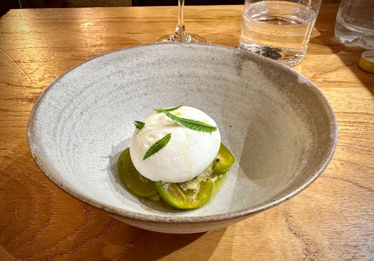 Semifreddo al pistacchio, composto da una pasta di pistacchi di Bronte e pistacchi greci tostati, servito come una pallina, con prugne verdi Reine-claude (una varietà tipica), spuma al fromage blanc, tagete
