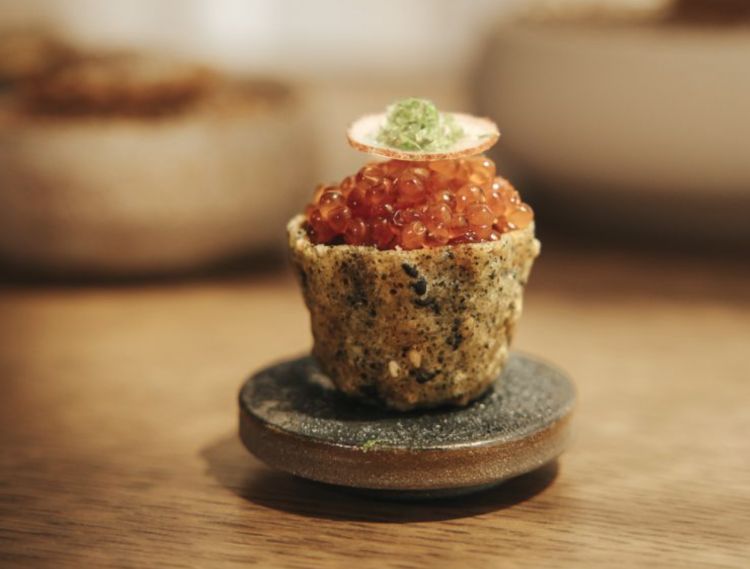 Un boccone iniziale esplosivo: tostada con semi di sesamo farcita con tartare di ricciola frollata 14 giorni, uova di trota e una spinta piccante, freschissima
