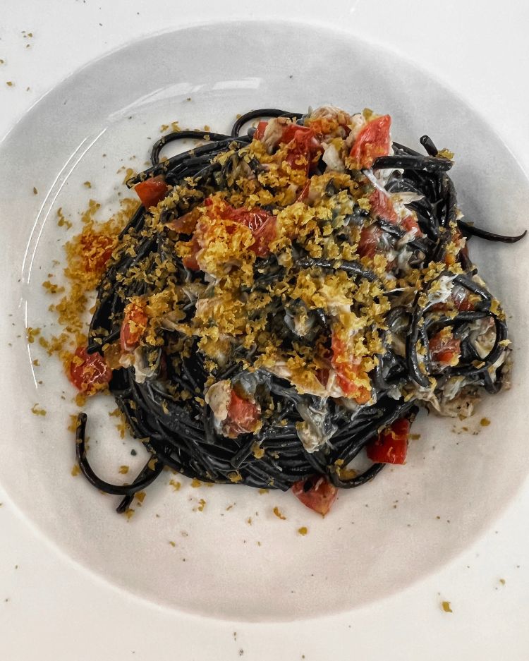 Spaghetto al nero di seppia con granchio blu, concassé di ciliegino, bottarga e olio evo al Tino Jesolo
