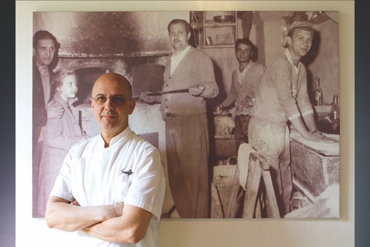 Pepe davanti alla foto in bianco e nero, appesa alla parete, che ritrae suo padre Stefano, fondatore nel 1961 della pizzeria. Foto Tuukka Koski
