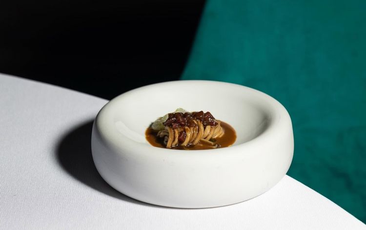 Tagliatella di cardoncello con scampo, un misto di terra e di mare. «Tutto il sottobosco assorbito dal cardoncello che si trasforma in questa occasione unica in una tagliatella, dal brodo e dal ragù di funghi e dalle prugne. E il mare?Una bisque leggera e delicata accompagnata da una tartare di scampi»