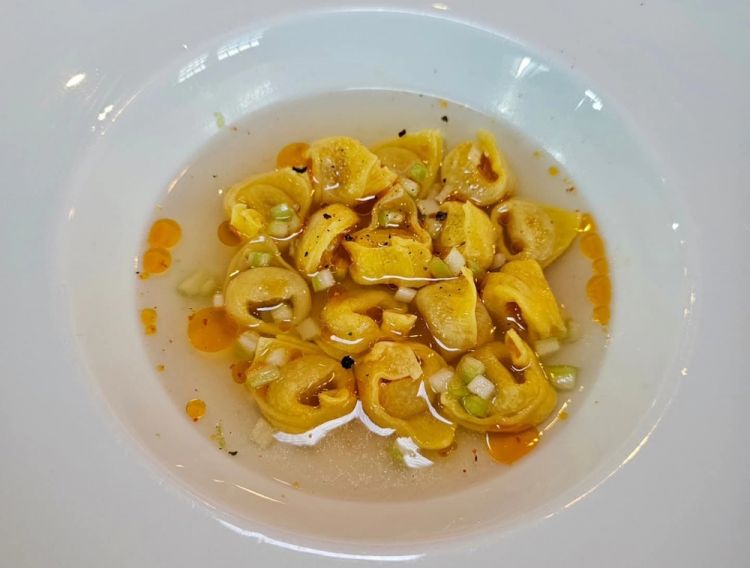 Tortellini in brodo ristretto di pollo, olio al peperone crusco e sedano
