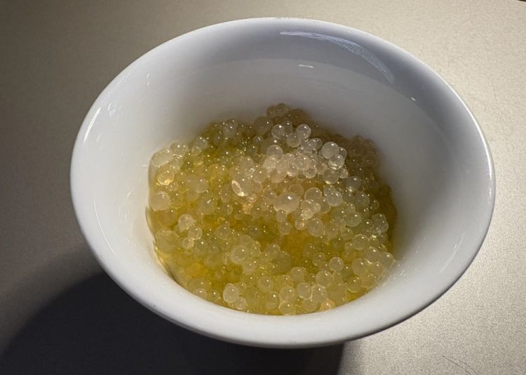 Uovo - Uovo cotto al vapore, caviale di aceto di mele ed erba cipollina
«E' uno dei pochi piatti di AlTatto che non ha stagione: in questa fase che stiamo vivendo da cinque anni, cambiamo menu tutti i mesi, sentiamo questo bisogno in questo momento. Invece l'uovo è un piatto che possiamo riproporre e ci è già capitato nell'ultimo anno e mezzo di inserirlo in carta più volte, cambiandolo leggermente. È un uovo ispirato a quello di Gualtiero Marchesi. Entrambe abbiamo fatto la scuola Alma e lì abbiamo incontrato Marco Soldati, che era il nostro maestro, diciamo di vita oltre che di cucina. Quindi ci ispiriamo a lui. L'uovo ha sotto una glassa di mele super ridotta e sopra un aceto di mele, con dentro una spezia che noi chiamiamo mix Soldati, perché lui ce la portò circa due anni fa: fiori di alloro, pepe nero, ginepro e un pochino di bergamotto. È un piatto a cui siamo legate anche emotivamente»