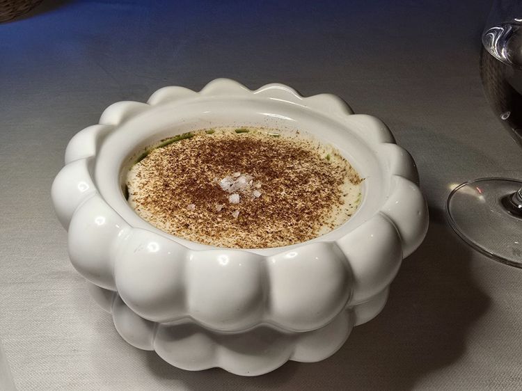 Cappuccino 4.0: caviale, ostrica, gelatina di limone, crème caramel di dashi di pelle di bottarga, zuppa di funghi, schiuma di latte con Masala. Un’opera di alta cucina che unisce elementi di mare e terra in una danza di sapori complessi e raffinati, caratterizzato da contrasti tra salato, acido, dolce e speziato. Il dashi, preparato con pelle di bottarga, conferisce un sapore umami profondo e marino, mentre la consistenza del crème caramel aggiunge una dolcezza delicata e una texture setosa