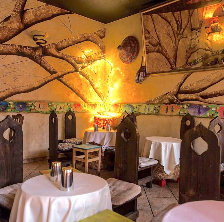 L'interno del ristorante Savana eritreo. Si può mangiare all'esterno, sui tavoli classici, o sui tavolini bassi che si chiamano Mosob, tipici dell'eritrea
