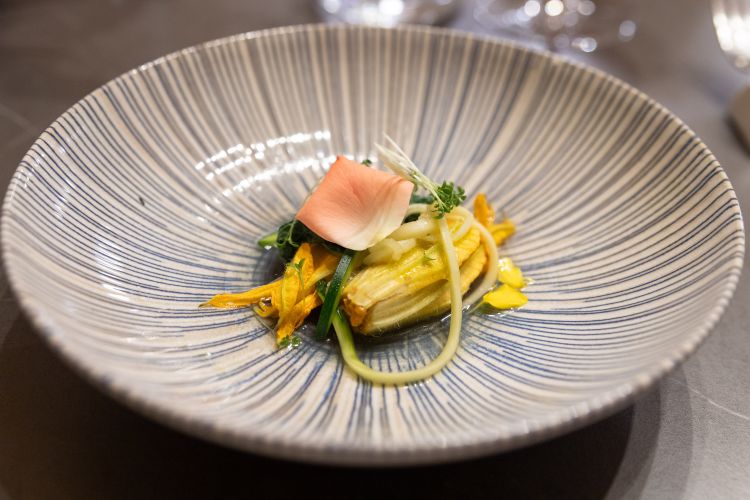 Zucchine in fiore, con fiore di zucca crudo ripieno con pesto di pomodoro secco e noci, acqua di minestra di tenerumi e zucchina a julienne