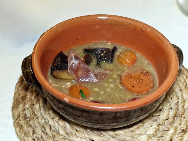 Cotture diverse e ottimizzate per gli ingredienti della superba Zuppa di lenticchie. La zuppa viene cotta in una “scapece” di lenticchie, la carota in un suo aceto, il mix di funghi (trombetta, portobello e pioppino) in un brodo di funghi stile nikkei. Il piatto è completato da un gel di pomodoro e da guanciale di wagyu e abbinato a un Pane di cristallo
